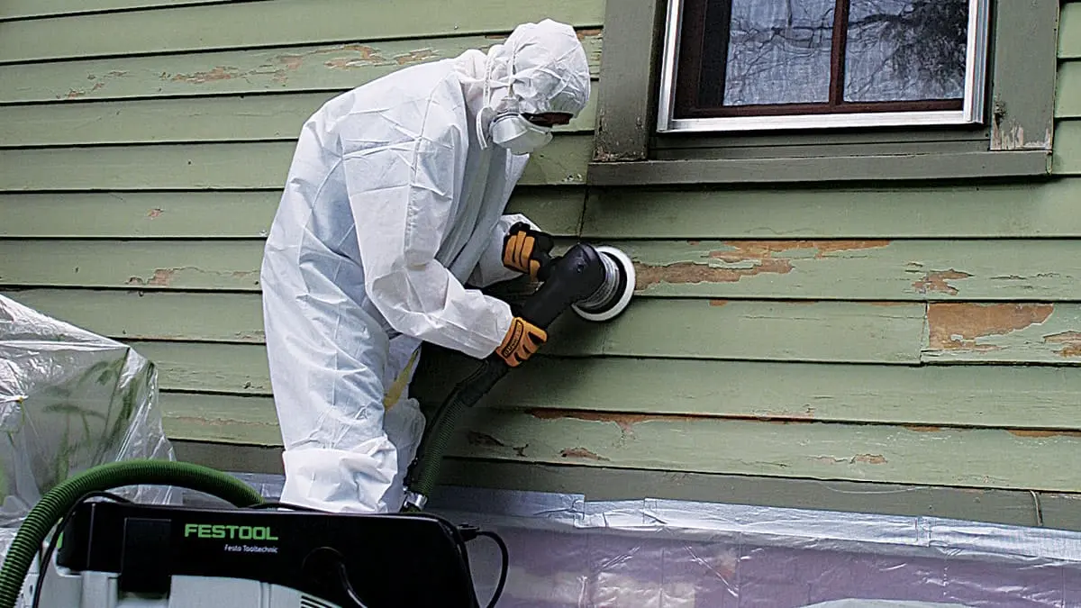 Renovation worker using protective equipment and controlled work practices on a painted surface